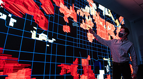 Person points to grid heat maps on large display screen.