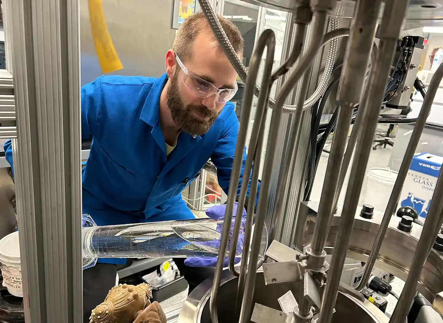 A researcher pours a liquid into a machine in a lab.