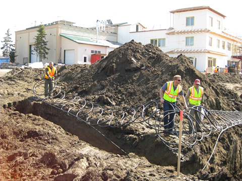 A tractor and construction workers dig trenches
