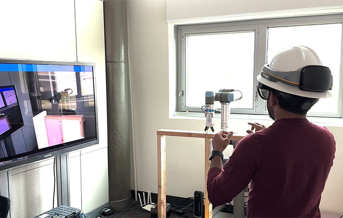 Person wearing hardhat in lab working with robotics equipment.