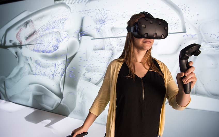 NREL Intern Alyssa Boll looks at a 3D rendering of ventilation in a car in the 3D Visualization Lab at NREL.