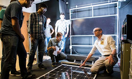 internships-grad-rpp-51985 Graduate students participating in the Hands-On PV Experience (HOPE) workshop work with NREL scientist Tim Silverman taking measurements and characterizations of 3-5 and crystalline silicon PV modules in the lab.
