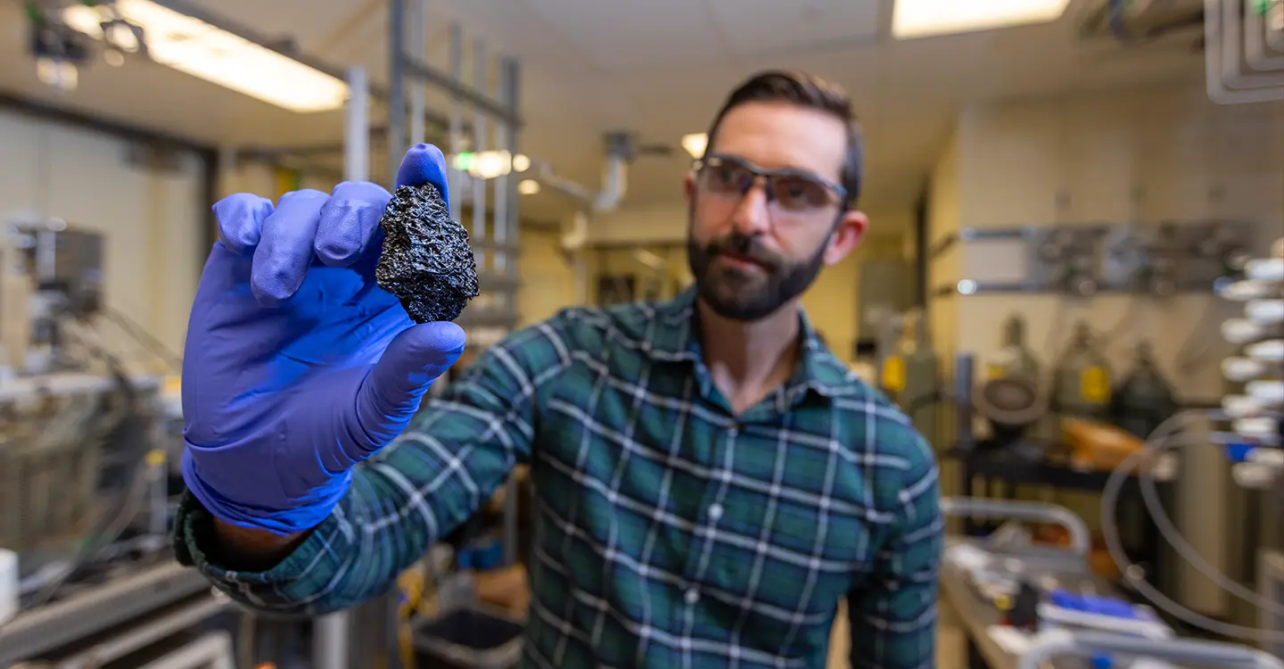 critical-minerals-094303 A researcher holds a chunk of bio-coke.