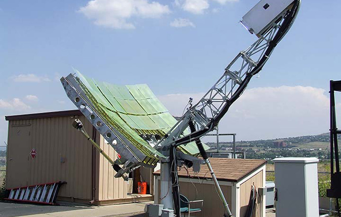A piece of equipment features a parabolic dish and sits outdoors in the twilight.