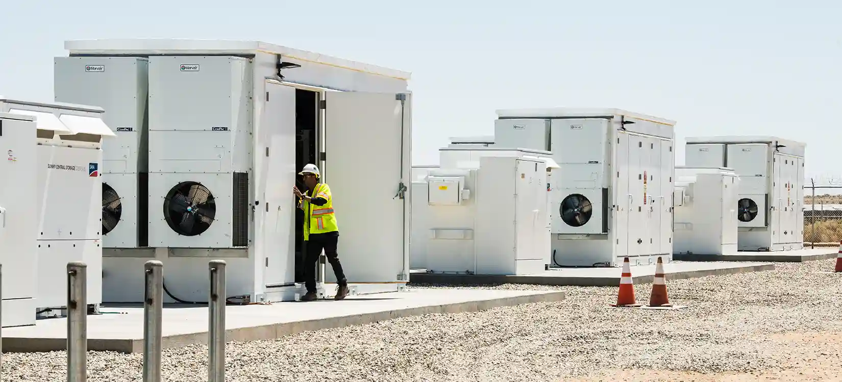 Worker looking in energy security storage unit outside.