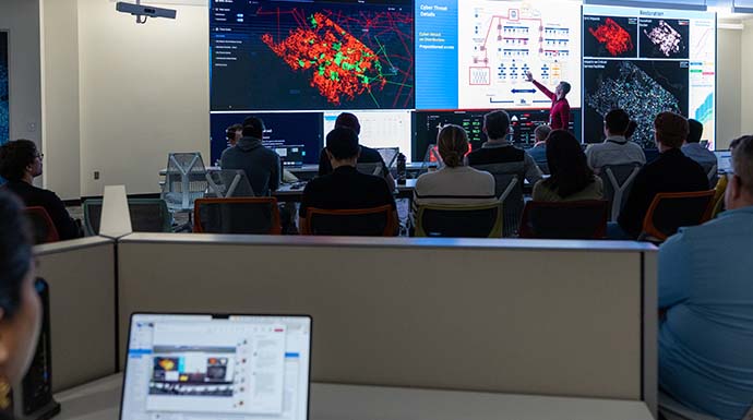 Researcher points to data on screen and gives presentation on cybersecurity research