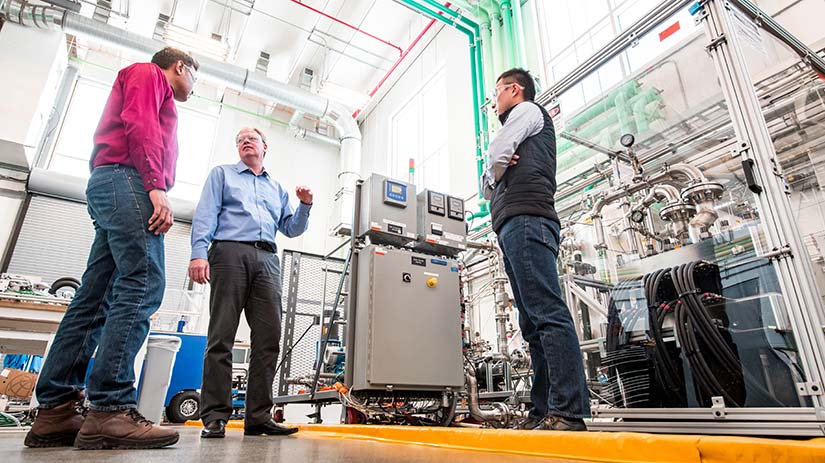 open-call-user-access-60019 Photo of three researchers talk in front of a hydrogen electrolyzer, one of the unique research capabilities of the ESIF.