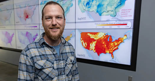 Researcher Ryan King stands in front of map data on presentation screen