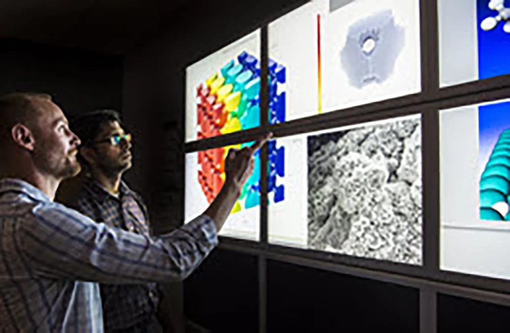 20260727-energy-discover-awaits-within-the-spin-of-atoms-analysis-characterization Two people looking at a large screen with 3D visualizations.