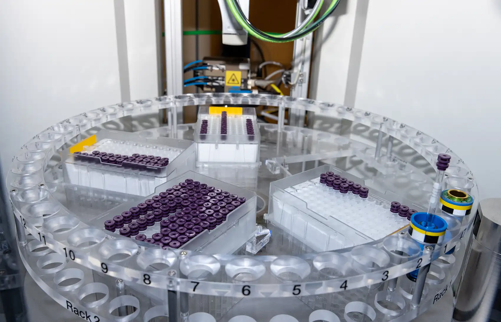 20260727-energy-discovery-awaits-within-the-spin-of-atoms-101592 Racks of purple-capped vials in a round autosampler.