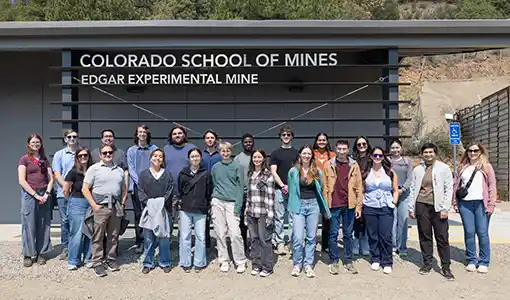 Continue reading about Twenty-two people standing outside a building with the text Colorado School of Mines Edgar Experimental Mine