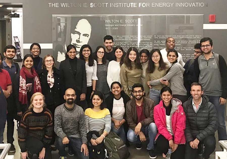 A large group of people posing in front of a sign that reads, 