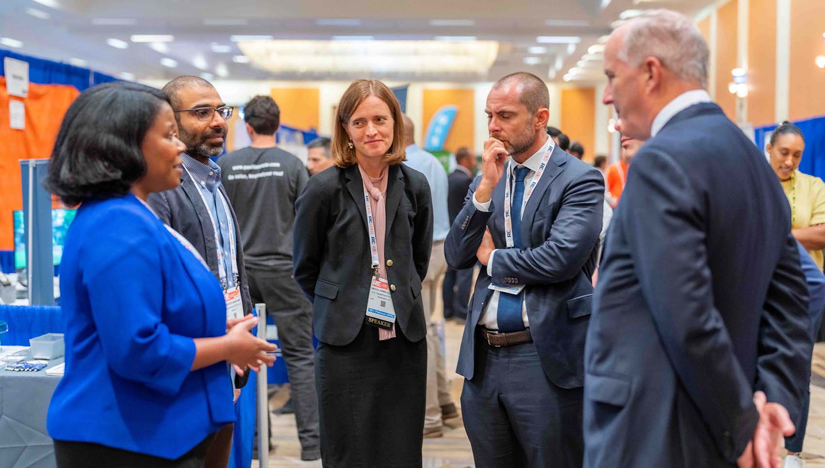 Six people talk in a circle in a conference hall.