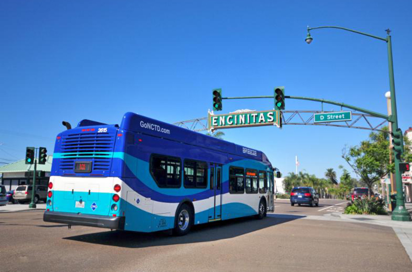 20250709-nrel-technical-support-empowers-local-governments-tribes-boost-energy-efficiency-cut-costs A bus drives under a sign that reads Encinitas.
