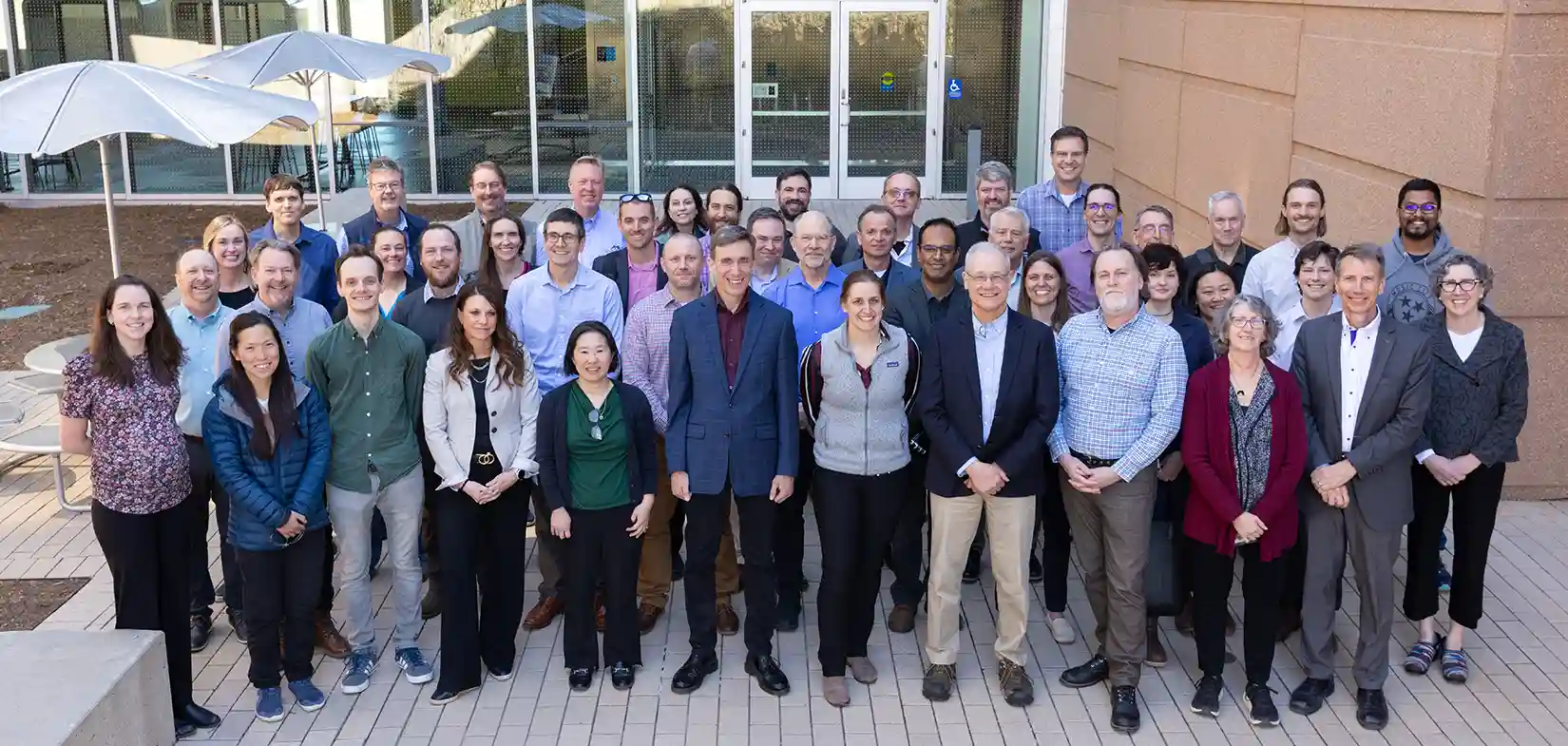 104813-full Group photo of approximately 40 researchers and staff posing outdoors at a research facility.