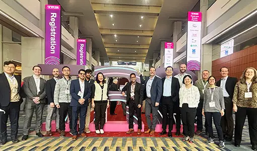 Continue reading about Sixteen people posing in front of TRB sign in large lobby.