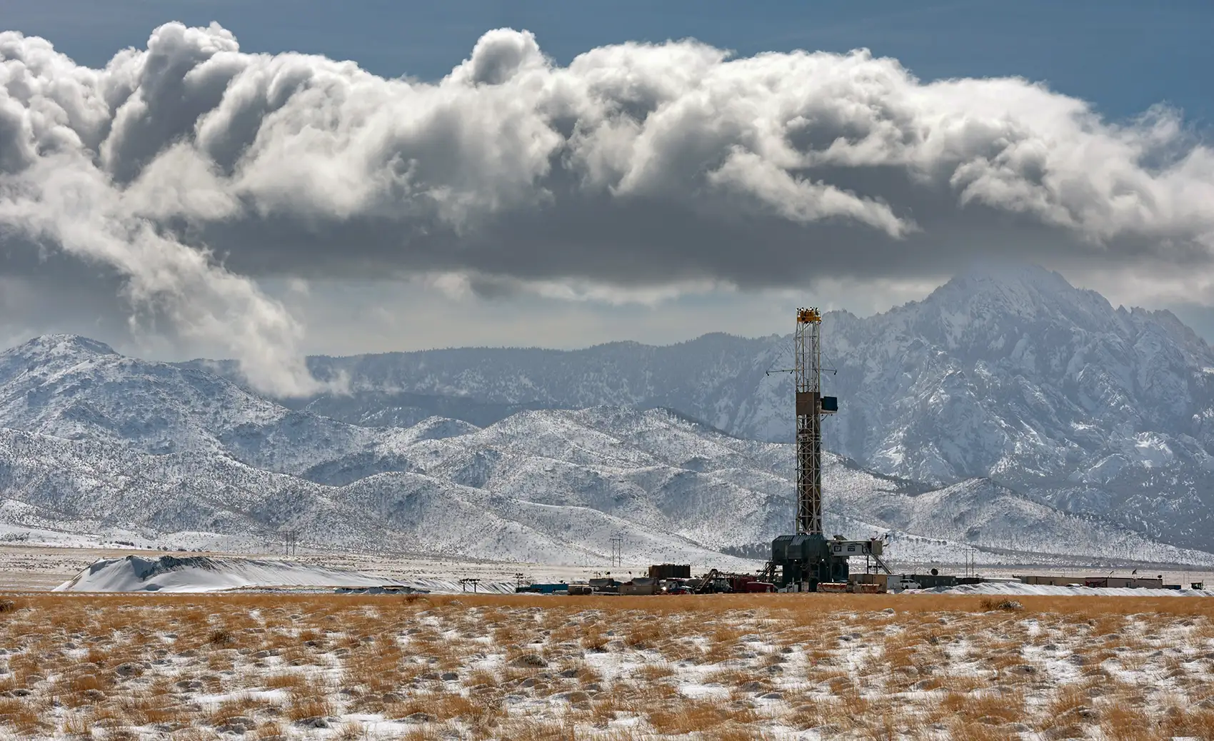 A geothermal station with clouds and mountains in the background.