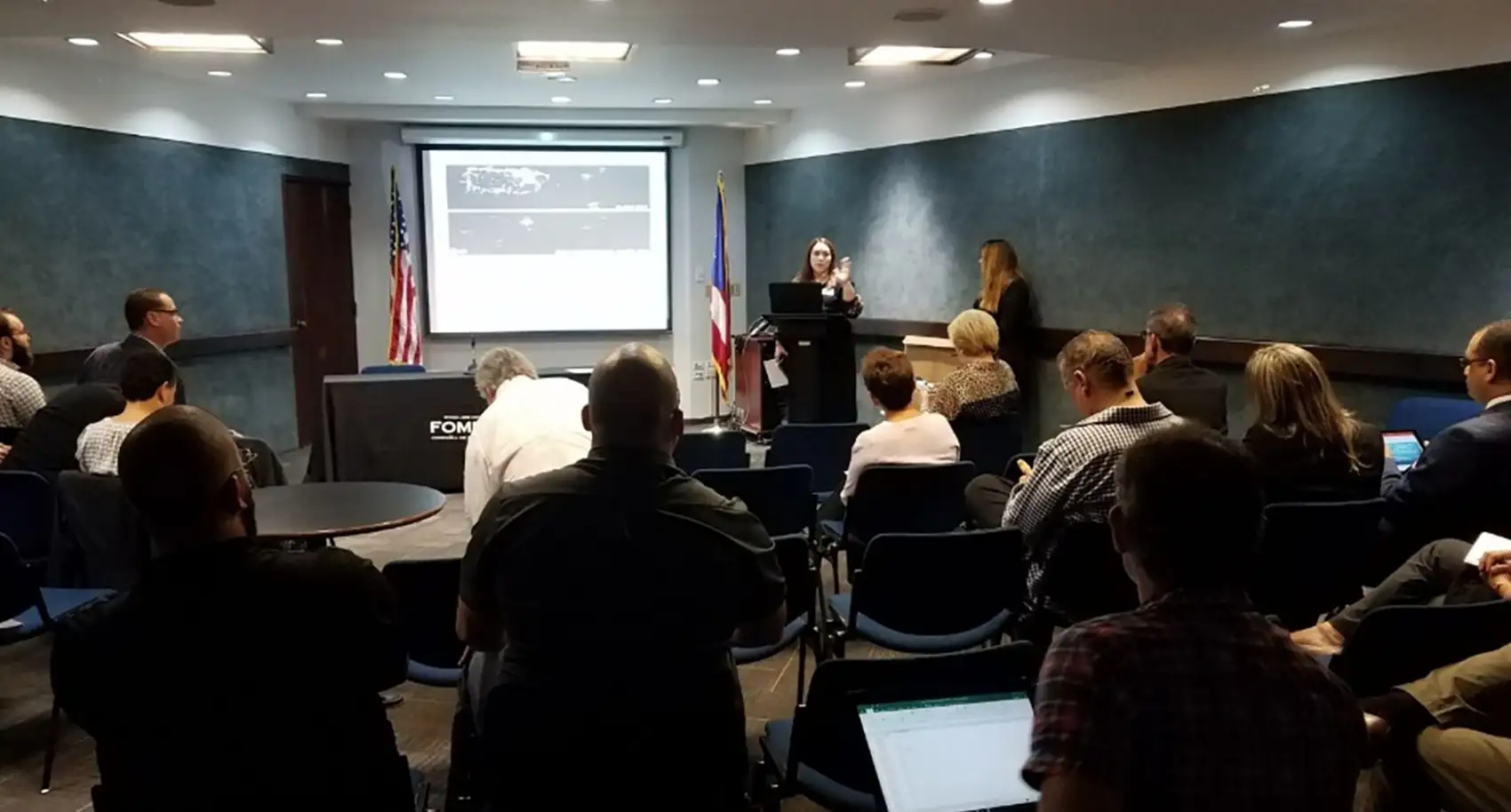 20260224-beneath-the-surface-glorynel-ojeda-matos-on-strengthening-the-systems-we-depend-on-stakeholder-forum A presenter speaking to a room full of people in front of a screen.