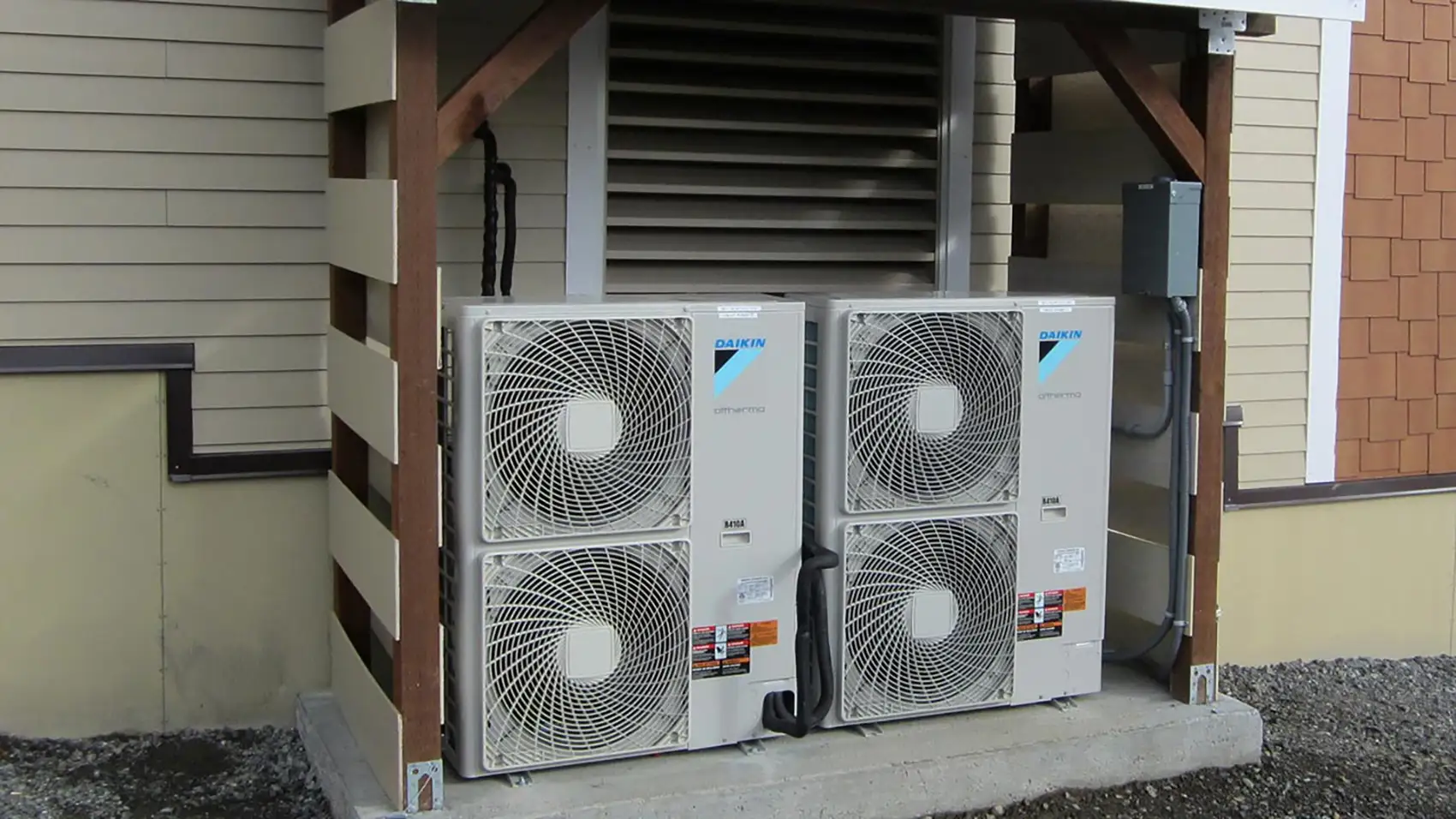 Two air source heat pumps installed on the exterior of a building.