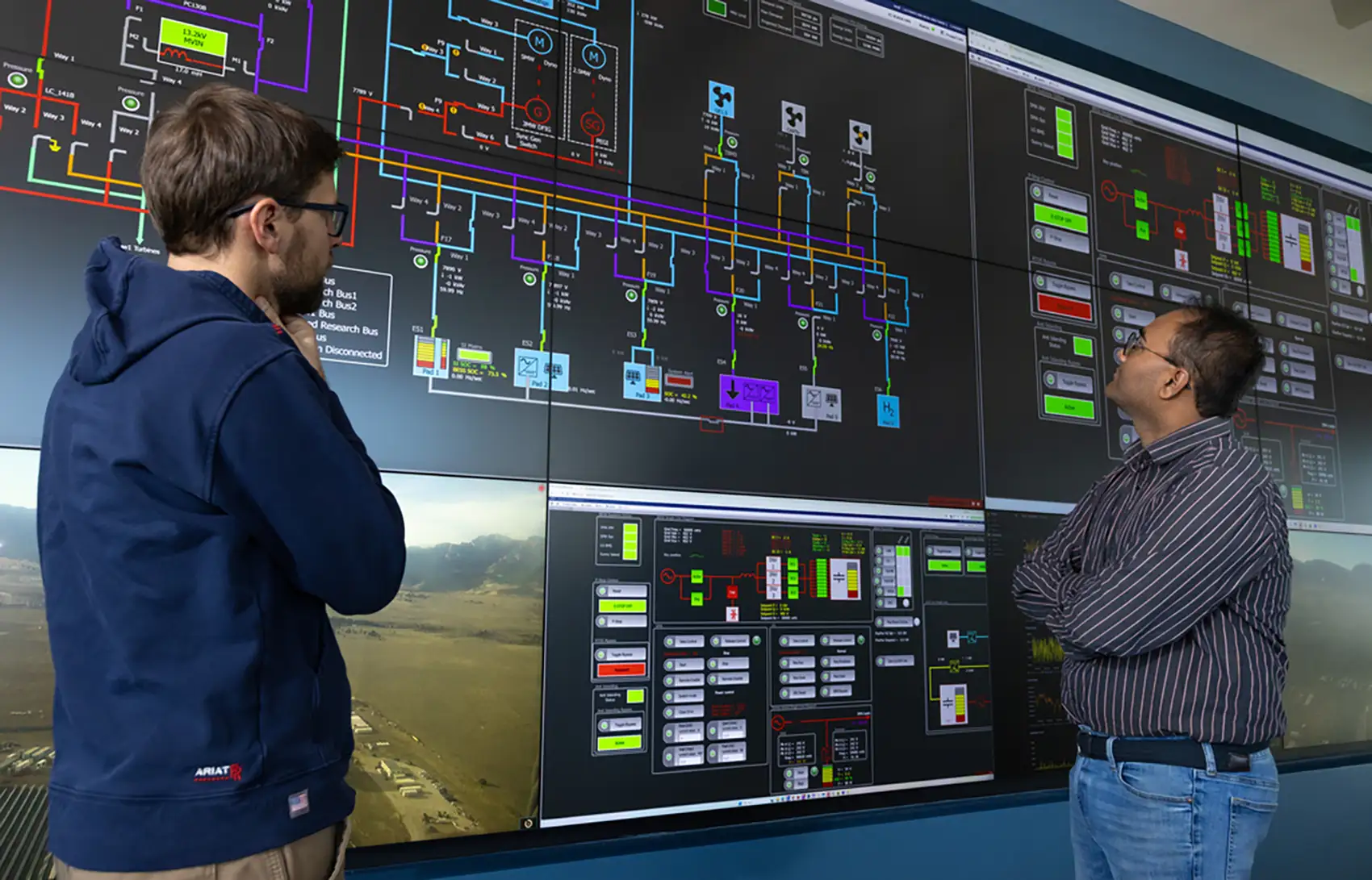 20260310-could-a-new-kind-of-power-supply-help-make-data-centers-grid-friendly-104515 Two people look at graphics on a large screen.