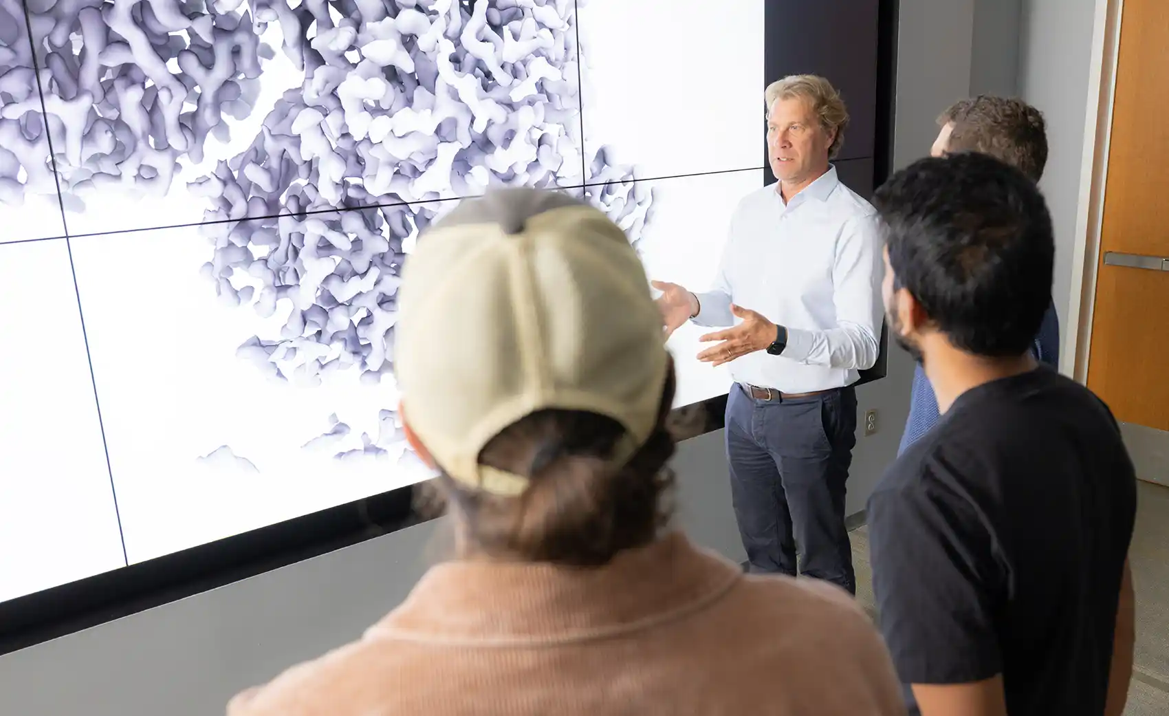 Four researchers discuss a rendering of an enzyme.