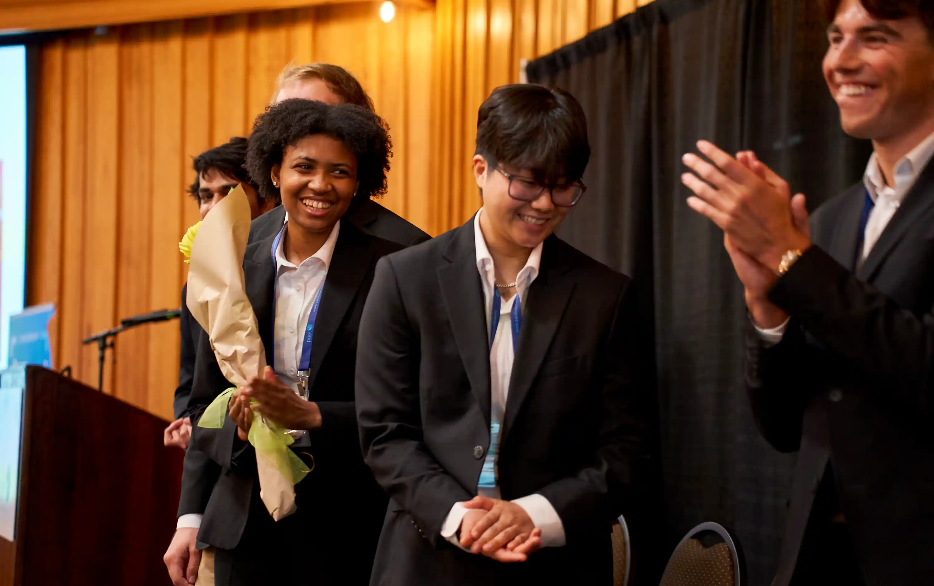Candid shot of five student competitors accepting an award on stage.