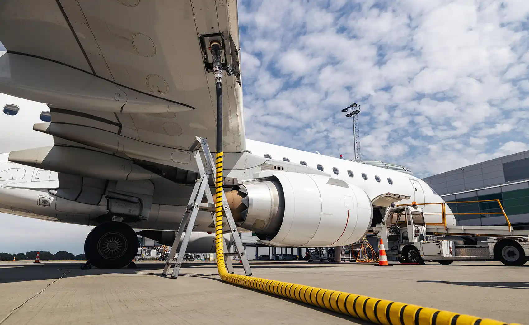 A parked airplane refuels using an aboveground fuel line.