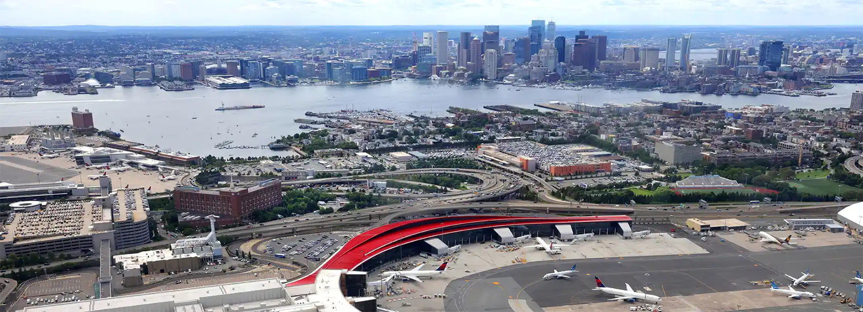Aerial view of an airport next to a body of water and a city skyline.
