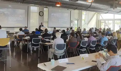 Continue reading about A room full of people in chairs facing a person giving a presentation.