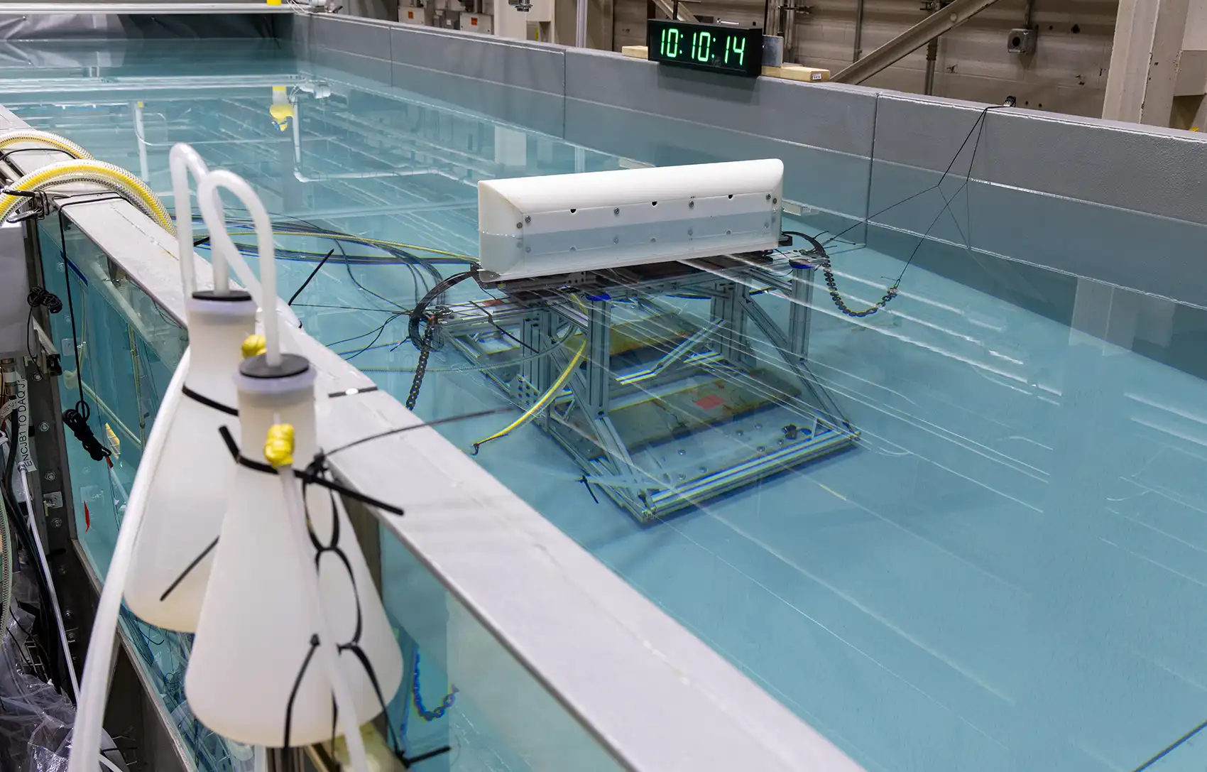 A wave tank in a laboratory showing the underwater testing apparatus inside the tank.