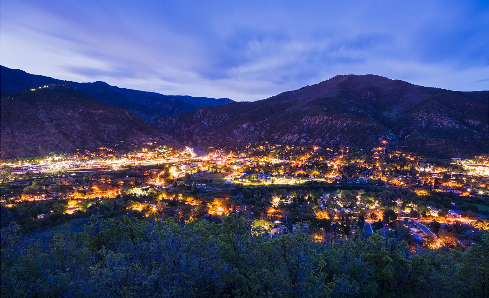 20260930-as-local-power-grows-utilities-reorganize-for-resilience-getty Overlooking town lit up at twilight with mountains in background.