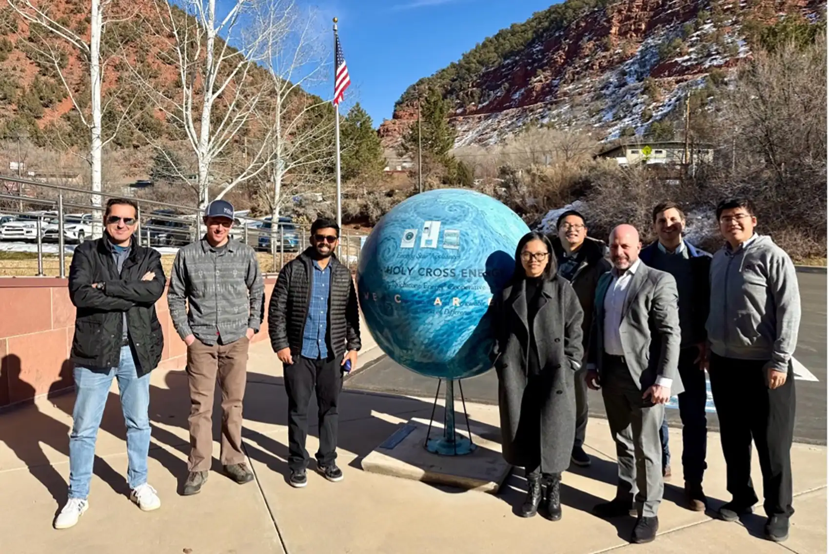 20260930-as-local-power-grows-utilities-reorganize-for-resilience-holy-cross-energy Eight people stand around a giant globe outside.