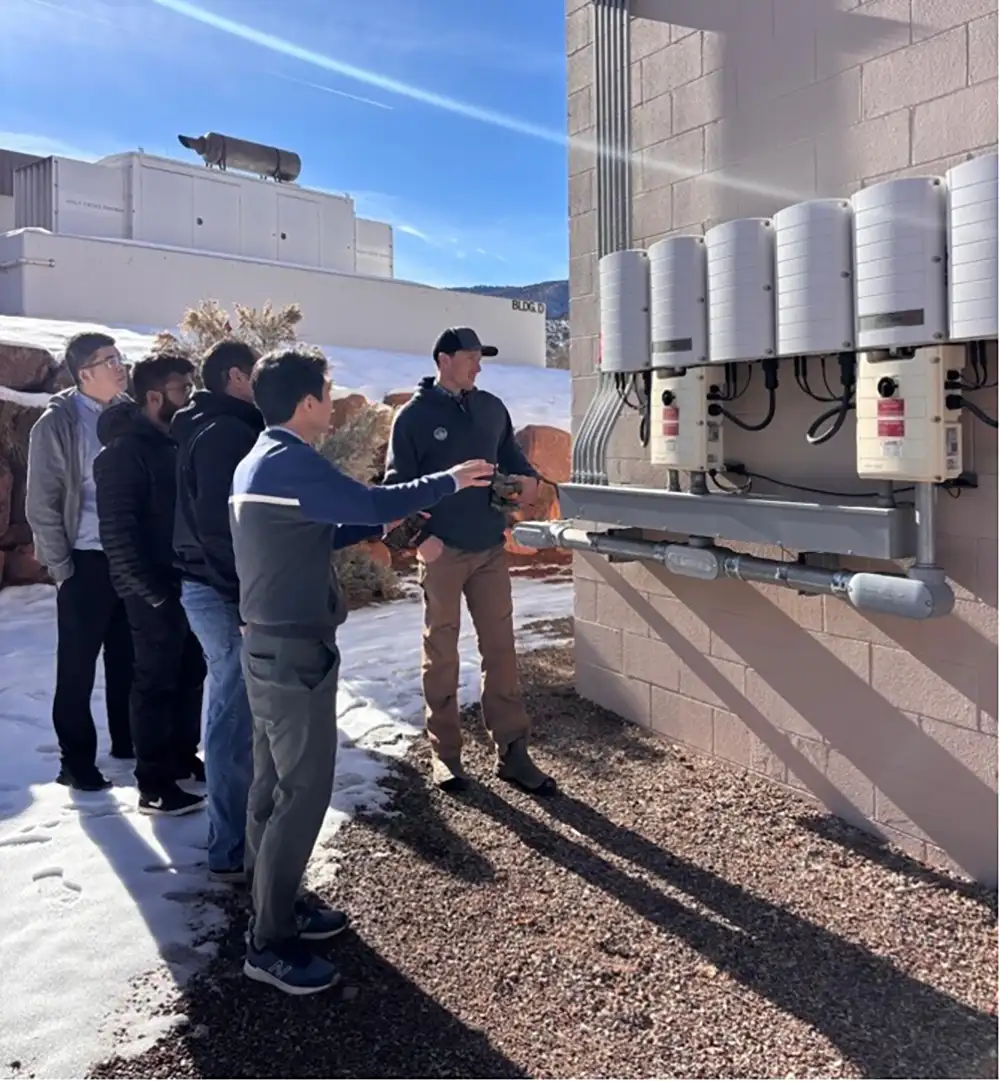 20260930-as-local-power-grows-utilities-reorganize-for-resilience-reorg-team A group of people look at a transformer on a building.