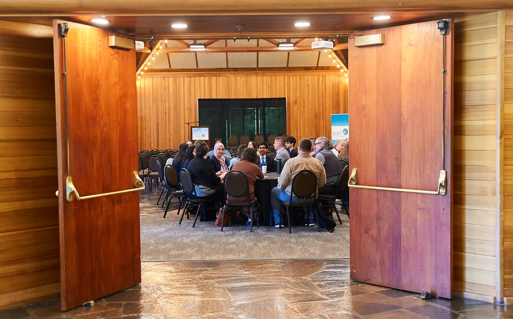 20261020-commercialization-hub-aims-to-ease-marine-energy-path-to-market--457 View through open doors of a small group of people seated around tables.
