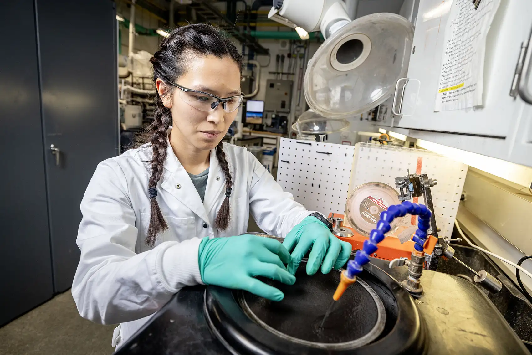 A researcher wearing gloves working in a sink with running faucet.