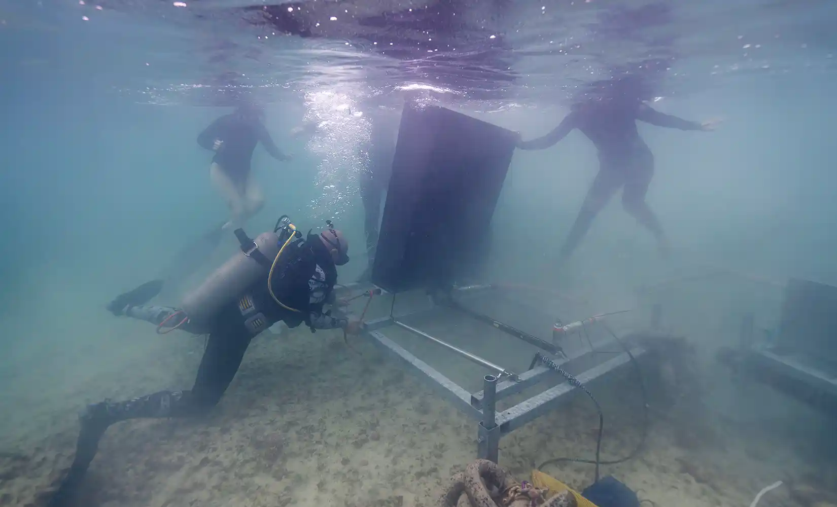 Divers under water deploying the SURF WEC device.