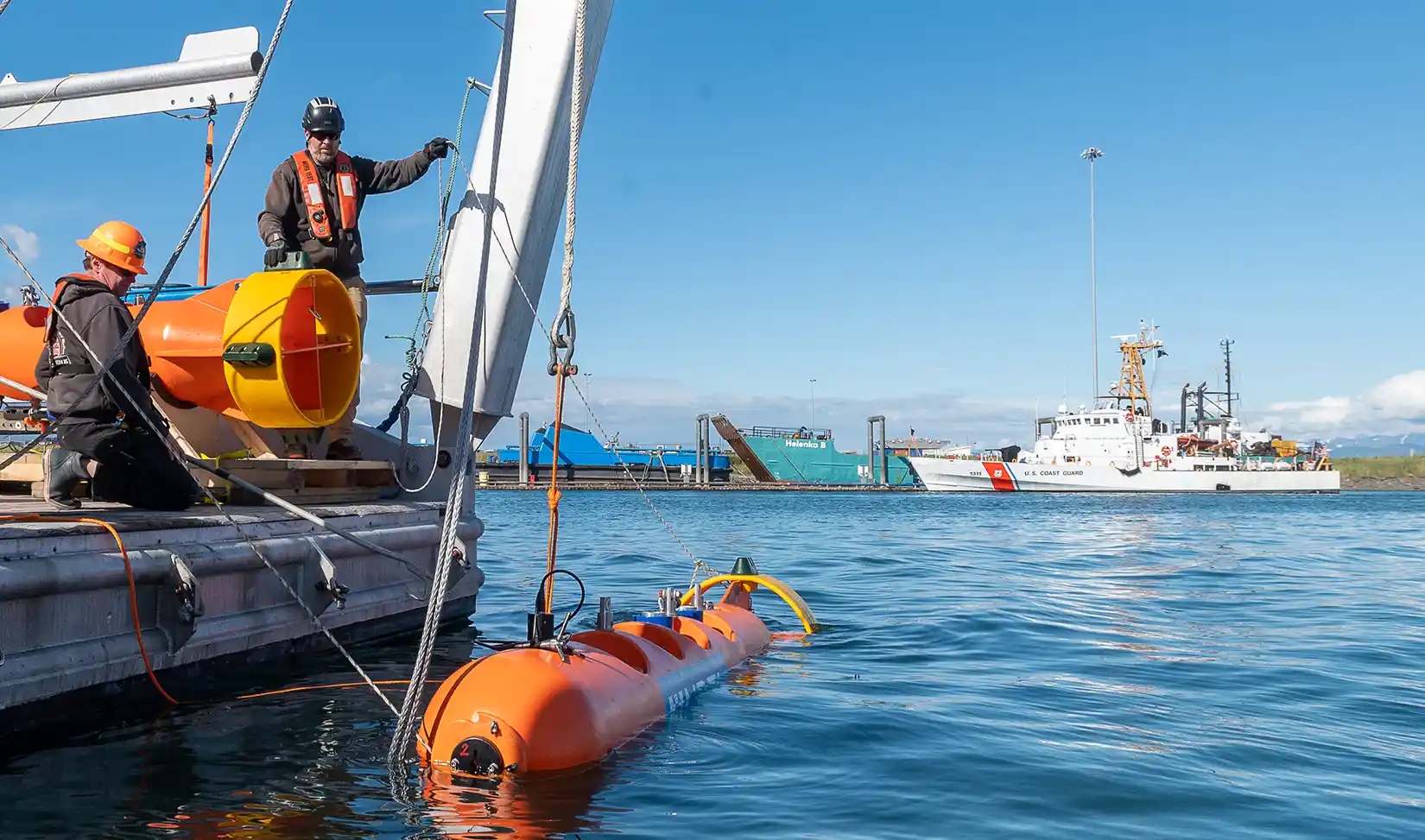 Researchers lower a marine energy device into the ocean.