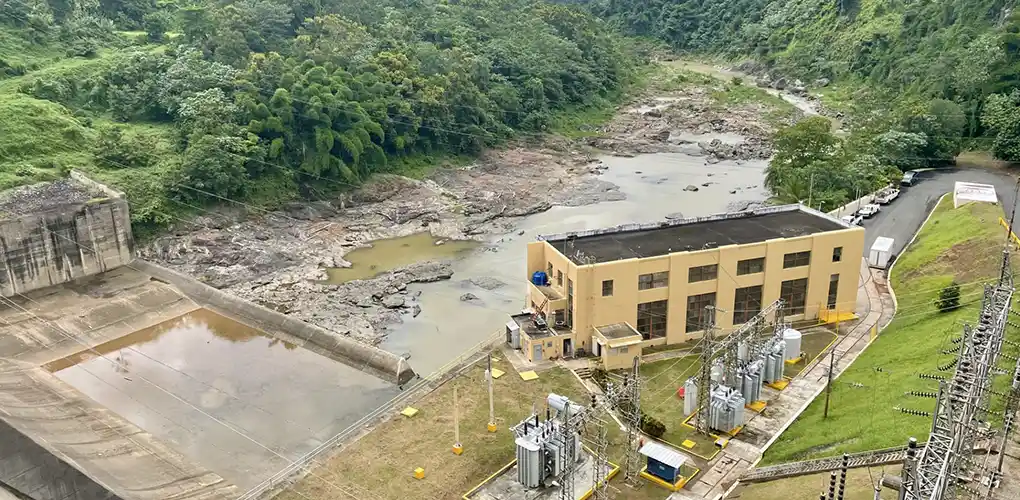 Hydropower dam with grid power lines and a muddy river.