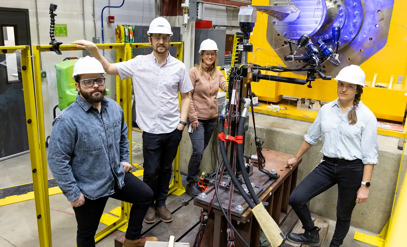 Four researchers stand in the lab next to 3D printer.