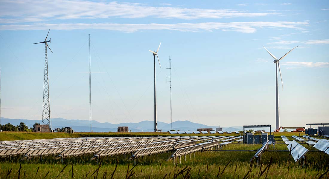 dswind-3dw-turbines-90318 Three small wind turbines with a solar photovoltaic array in the foreground and mountains in the background.